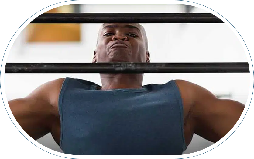 Man in need of low back pain treatment stretching his back at the gym.