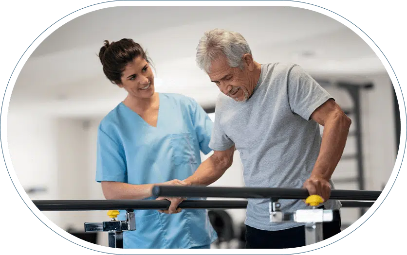 Young woman doctor in scrubs helping her older male patient with his walking rehabilitation using alternative therapies.