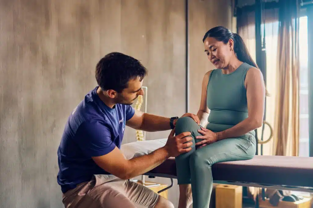 Physiotherapist examining knee of female runner with knee pain.
