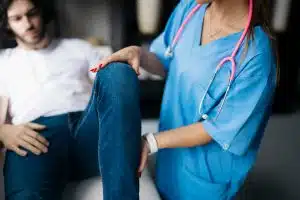 A close-up view of an orthopedic doctor examining a patient's injured knee in a clinic.