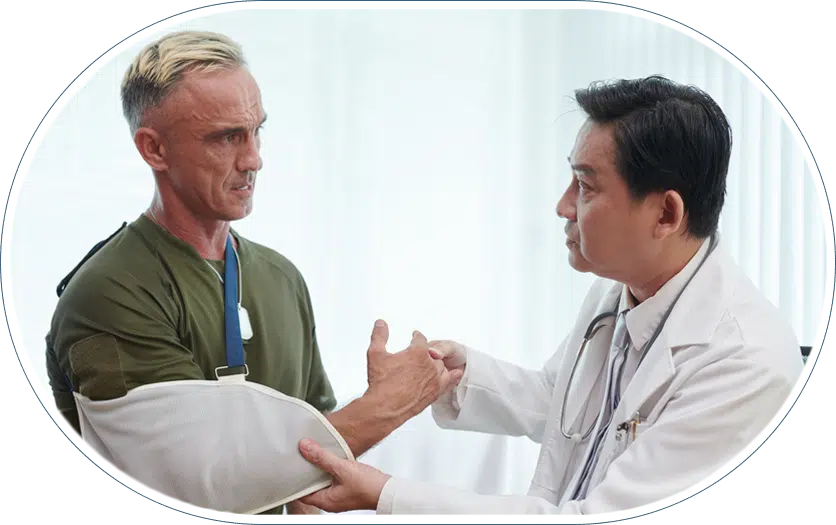 Orthopedic doctor examining male patient with arm in sling for rotator cuff injury