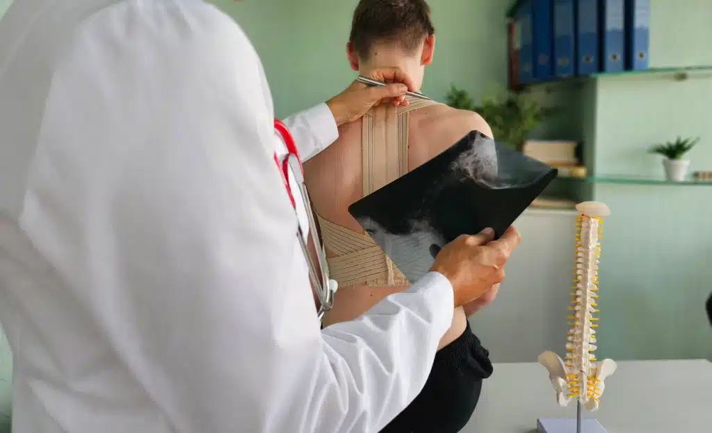 An orthopedic spine specialist examining a patient with a spinal injury in a medical facility during a treatment session.