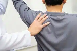 An orthopedic surgeon for shoulder revision is examining the shoulder of a young man in the clinic.