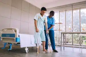 A healthcare provider helping a patient recover from a hip operation.